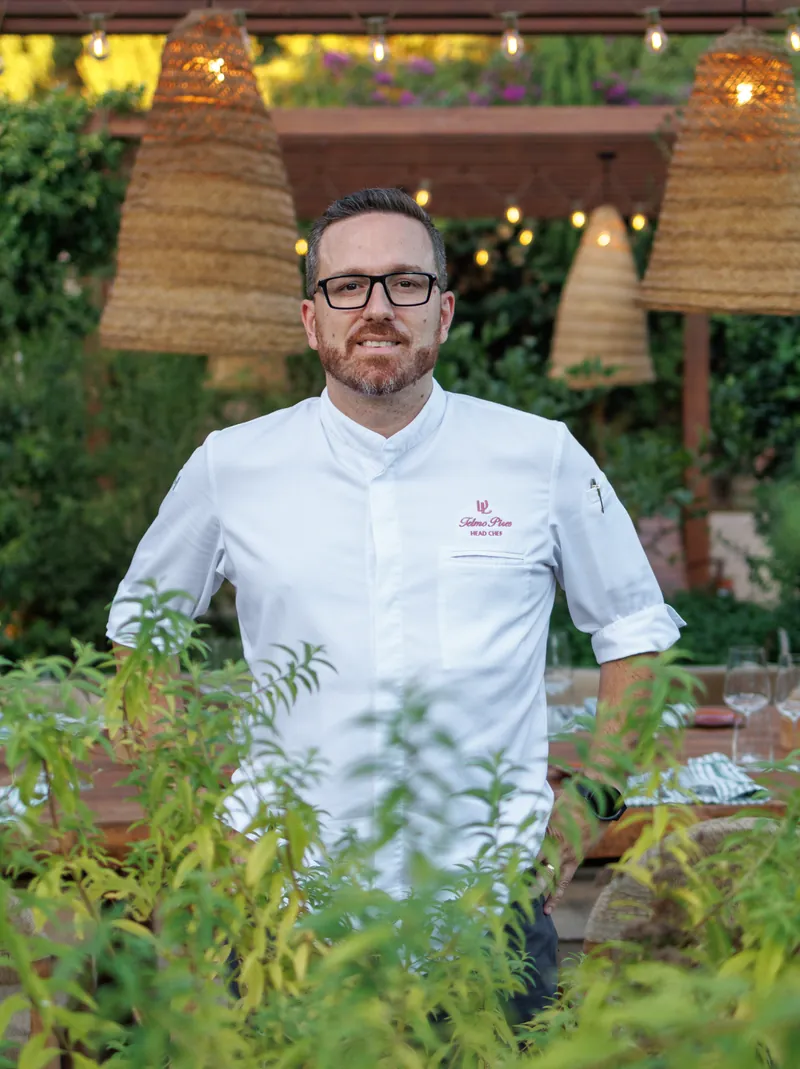 Chef Telmo Pires under the lanterns at Raízes, the kitchen garden in front of him