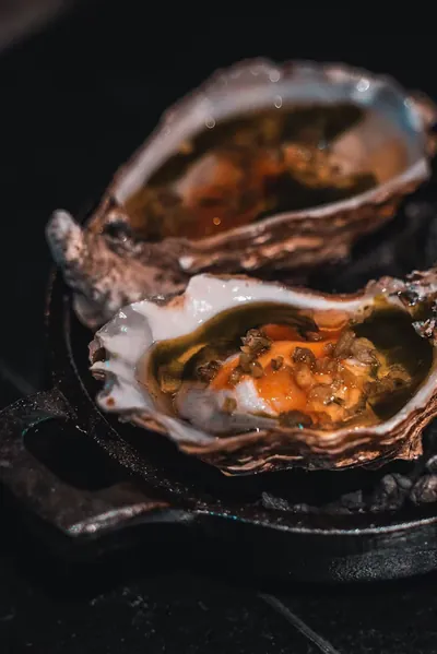 Oysters grilled over embers in a cast-iron dish