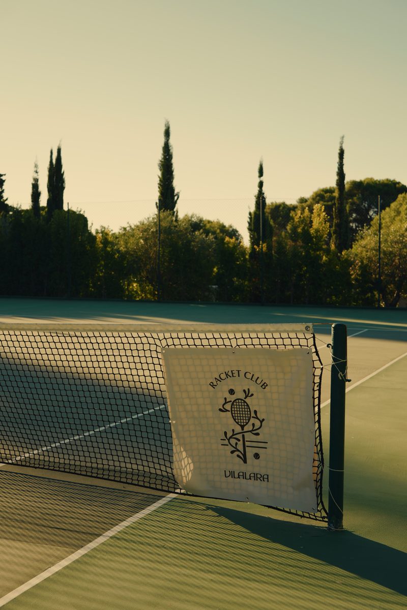 The Vilalara Racket Club banner on the net, cypresses behind, in the evening light