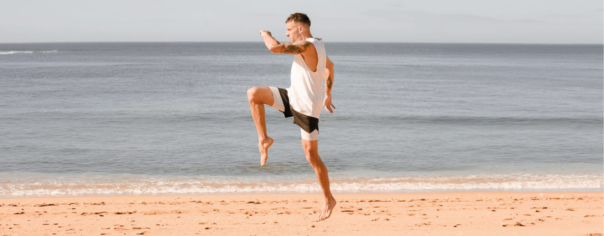 A man training on the beach by the sea